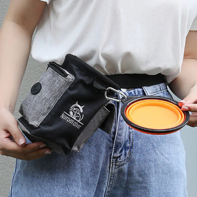 Black dog outdoor training bag worn around waist, featuring compartments and attached orange collapsible bowl.